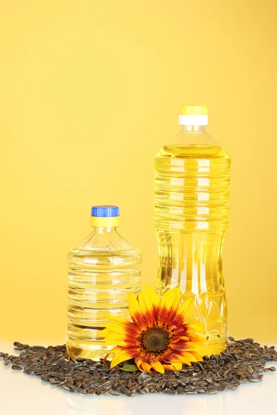 Подсолнечное масло в пластиковых бутылках на желтом фоне — стоковое фото