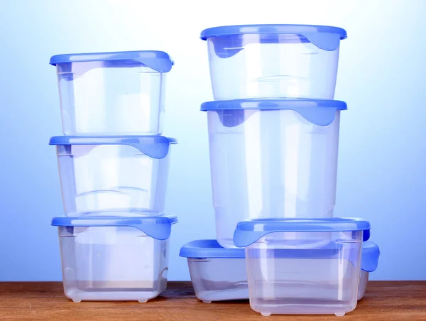Contenitori di plastica per alimenti su tavolo di legno su sfondo blu — Foto Stock