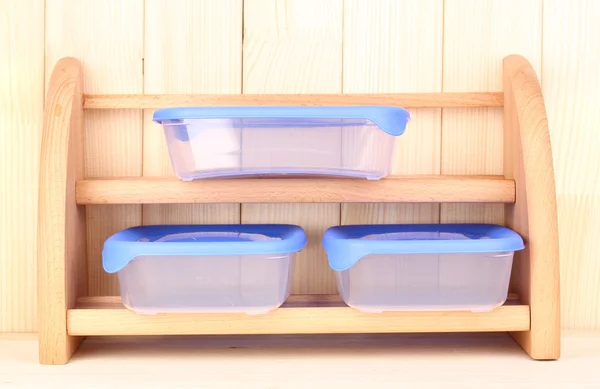 Envases de plástico para alimentos en estante sobre fondo de madera — Foto de Stock