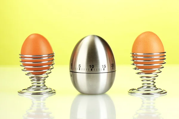 Timer uovo e uovo in metallo stand su sfondo verde — Foto Stock