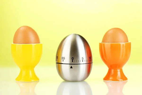 Temporizador de huevo y huevo en color de pie sobre fondo verde — Foto de Stock