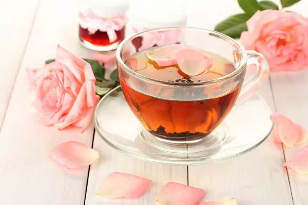 Xícara de chá com rosas e geléia na mesa de madeira branca — Fotografia de Stock