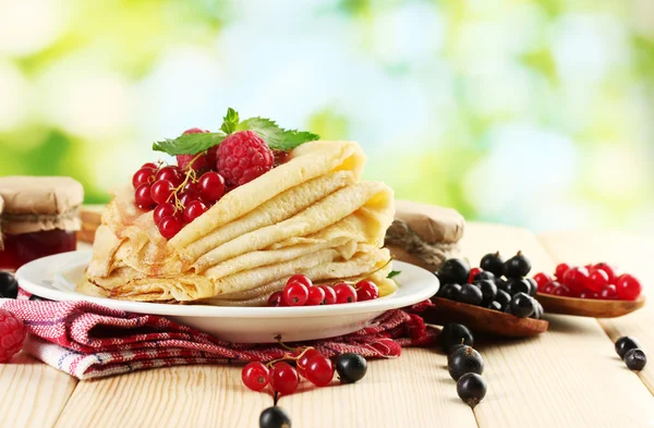 Pfannkuchen mit Beeren, Marmelade und Honig auf Holztisch auf grünem Hintergrund — Stockfoto