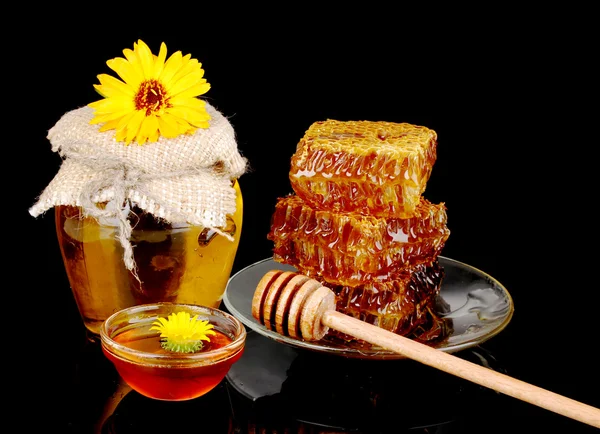 Frasco de mel e favo de mel sobre fundo preto — Fotografia de Stock
