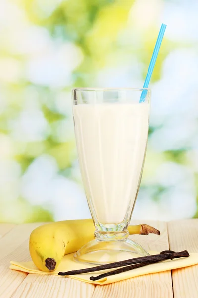 Bananenmilchshake auf Holztisch vor hellem Hintergrund — Stockfoto