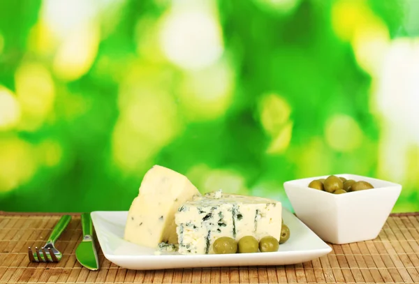 Samenstelling van blauwe kaas en olijven op helder groene achtergrond close-up — Stockfoto