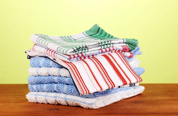 Кухонные полотенца на деревянном столе на зеленом фоне крупным планом — стоковое фото