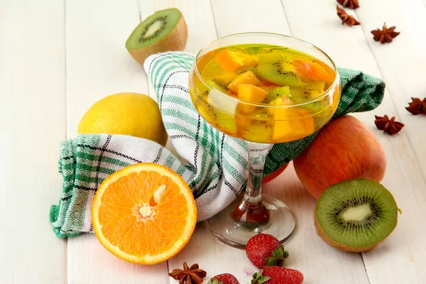 Punch in glass with fruits, on white wooden table — Stock Photo, Image