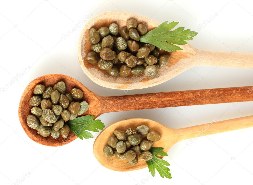 Green capers in wooden spoons on white background close-up
