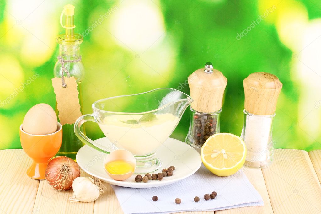 Mayonnaise in bowl on wooden table on nature background