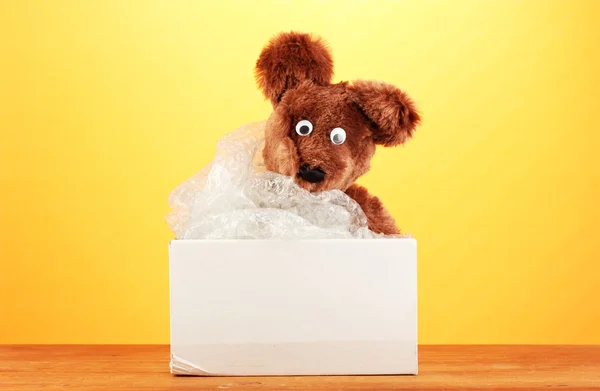 stock image Opened parcel with a child's toy on yellow background close-up