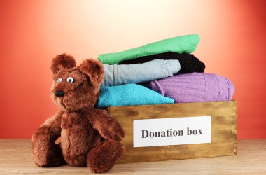 Donation box with clothing on red background close-up clipart