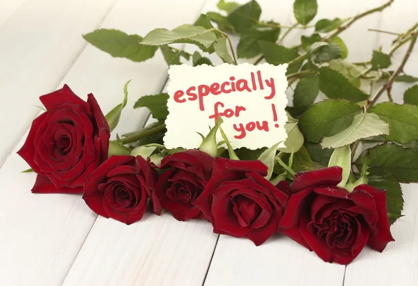 Ramo de rosas rojas con nota en una mesa de madera blanca de cerca —  Fotos de Stock