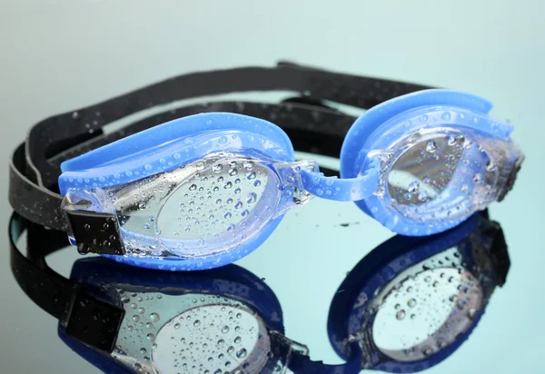 Blauwe zwemmen bril met druppels op blauwe achtergrond — Stockfoto