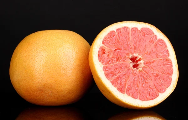 Rijp grapefruit en de andere helft geïsoleerd op zwart — Stockfoto