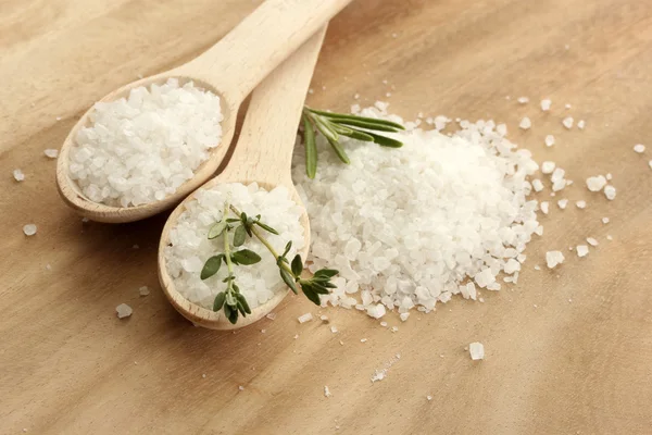 Соль в ложках со свежим розмарином и тимьяном на деревянном фоне — стоковое фото