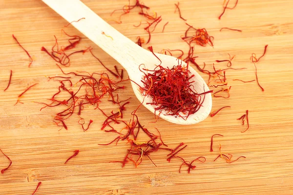 Stigmas of saffron in wooden spoon on wooden background close-up — Stock Photo, Image