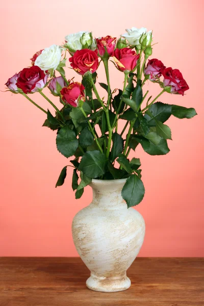 Krásná růže ve váze na červeném pozadí detail — Stock fotografie