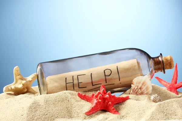 Glasflaska med en märka insida på sand, på blå bakgrund — Stockfoto
