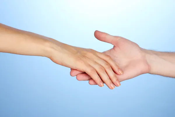Women's hand goes to the man's hand on blue background — Stock Photo, Image