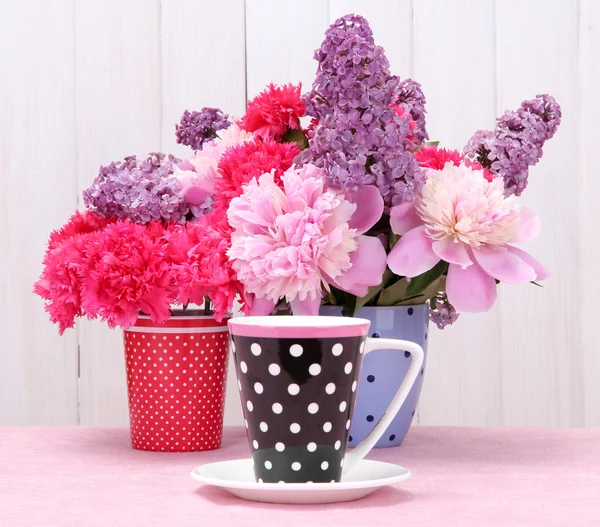 春の花と白い木製の背景上のテーブルの上にカップ — ストック写真