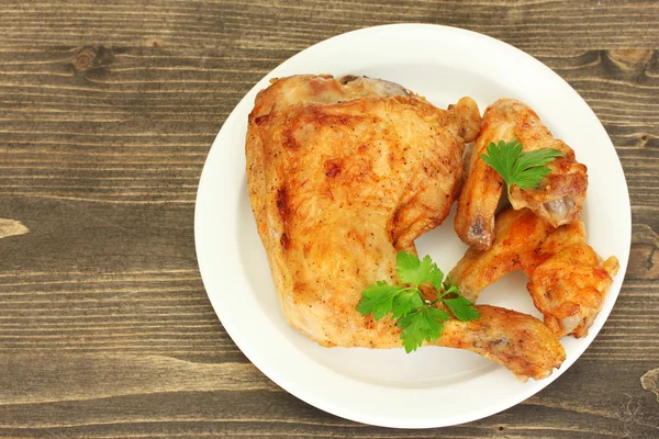 Alitas de pollo tostadas y pierna con perejil en el plato sobre fondo de madera — Foto de Stock