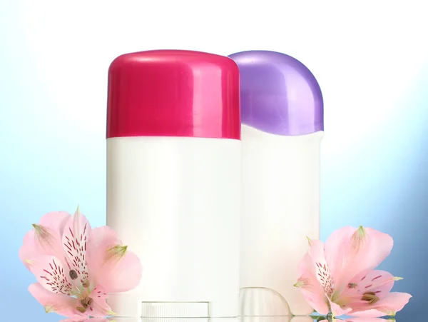Deodorant met bloemen op blauwe achtergrond — Stockfoto