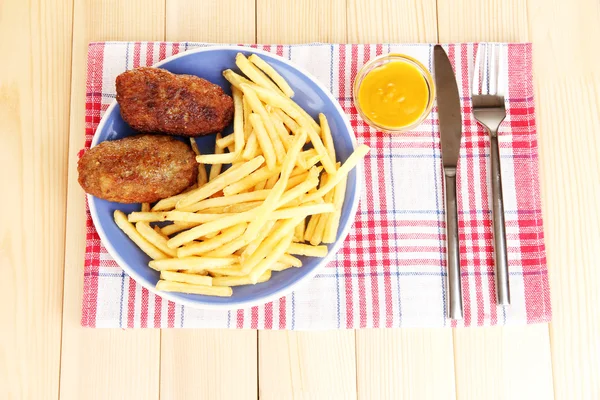 Patatas fritas con hamburguesas en el plato sobre fondo de madera primer plano — Foto de Stock