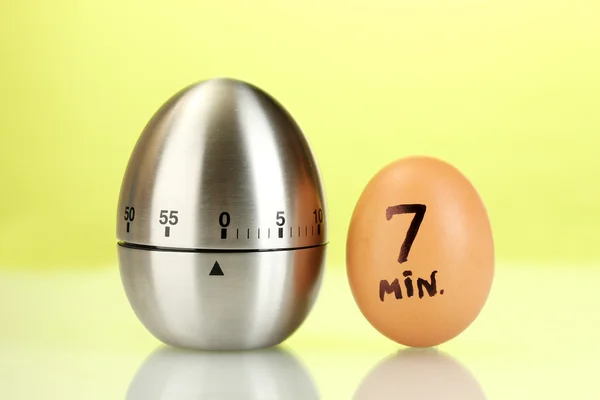 Egg timer and egg on green background — Stock Photo, Image