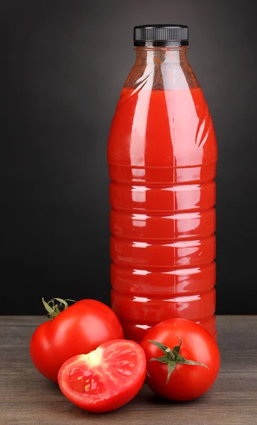 Jugo de tomate en botella sobre mesa de madera sobre fondo gris —  Fotos de Stock