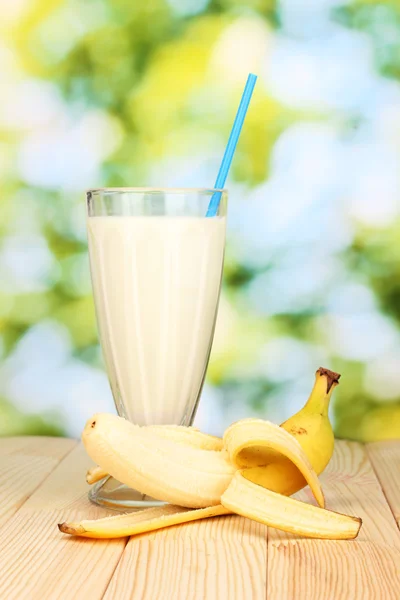 Banana milk shake on wooden table on bright background — Stock Photo, Image