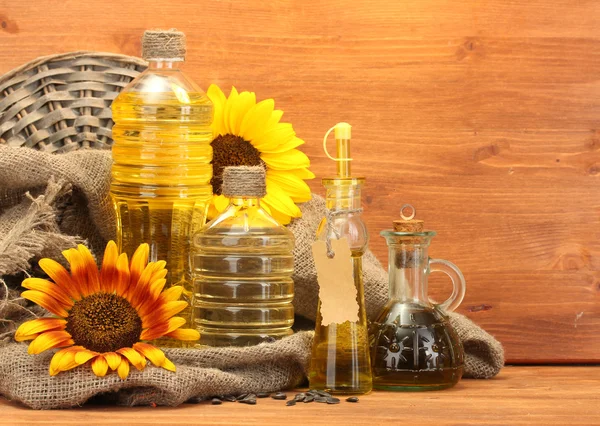 Olej v lahví, slunečnice a semen, na dřevěné pozadí — Stock fotografie
