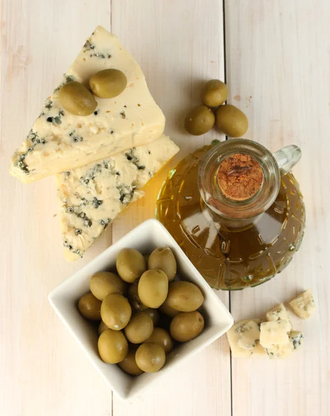 Kaas met schimmel en karaf van olijfolie op witte houten achtergrond close-up — Stockfoto