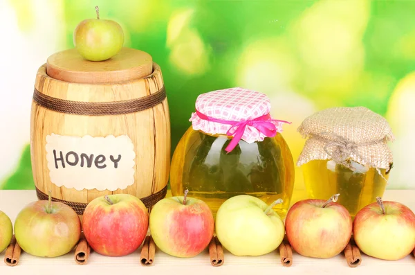 Honey and apples with cinnamon on wooden table on natural background — Stock Photo, Image
