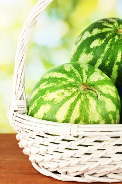 Ripe watermelon in wicker basket on green background close-up — Stock Photo, Image