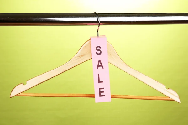 Дерев'яна вішалка для одягу як символ продажу на зеленому фоні — стокове фото