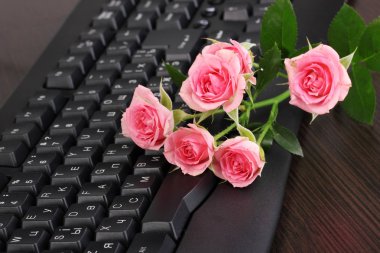 Pink roses on keyboard close-up internet communication