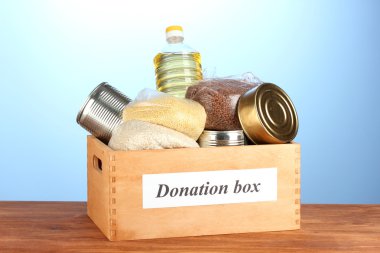 Donation box with food on blue background close-up clipart