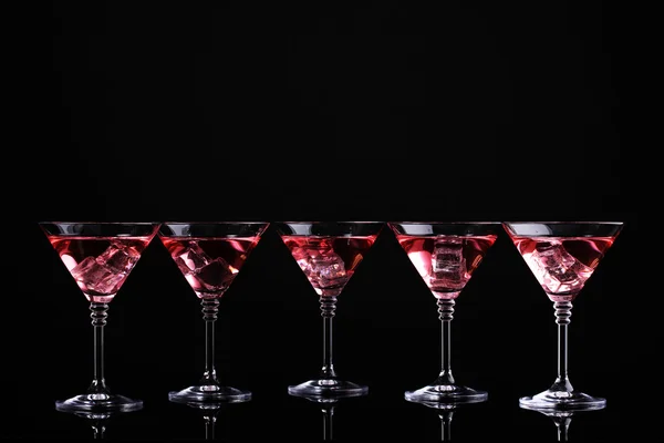 Красный коктейль в бокалах мартини, изолированных на черном — стоковое фото