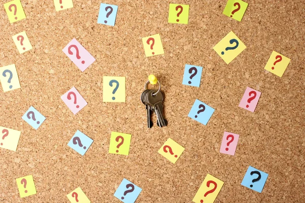 Schlüssel mit vielen Fragezeichen auf Korkplatte — Stockfoto