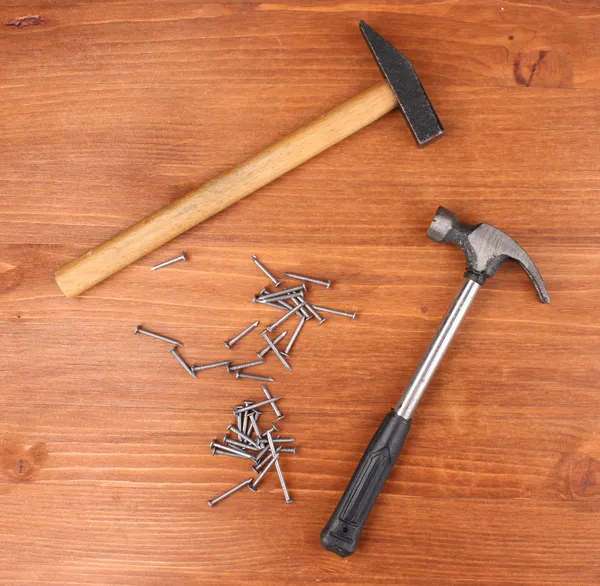 Martelos e pregos de metal no fundo de madeira — Fotografia de Stock