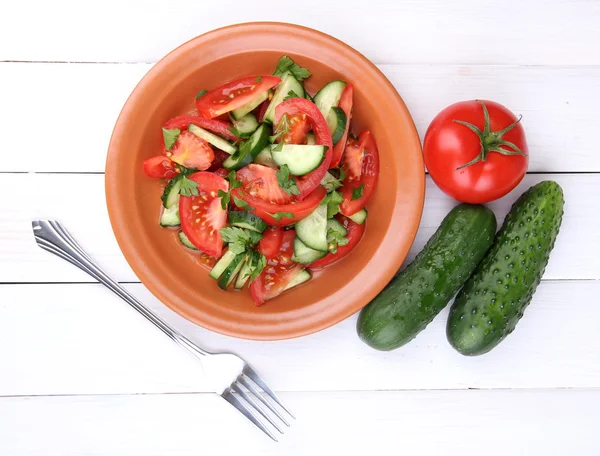 Čerstvý salát s rajčaty a okurkami na bílém pozadí dřevěná — Stock fotografie