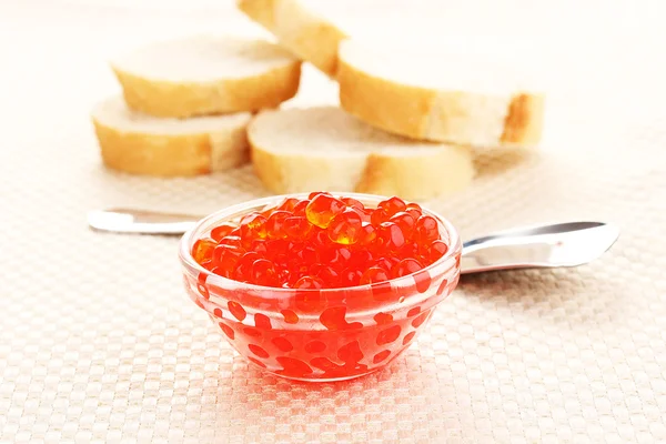 Χαβιάρι κόκκινο σε γυάλινο μπολ με ψωμί και κουτάλι σε ύφασμα — Φωτογραφία Αρχείου