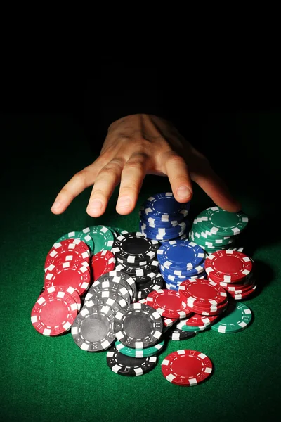 Покерные фишки и рука над ним на зеленом столе — стоковое фото