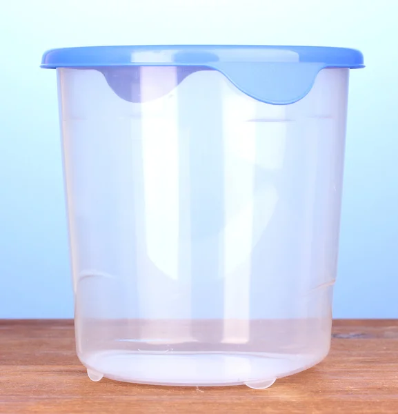 Plastic container voor voedsel op houten tafel op blauwe achtergrond — Stockfoto