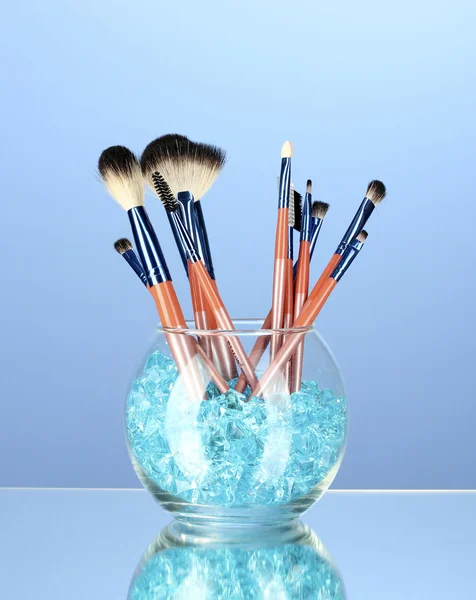 Make-up-Pinsel in einer Schüssel mit Steinen auf blauem Hintergrund — Stockfoto