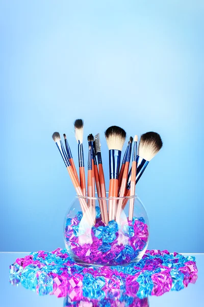 Make-up sikat dalam mangkuk dengan batu di latar belakang biru — Stok Foto
