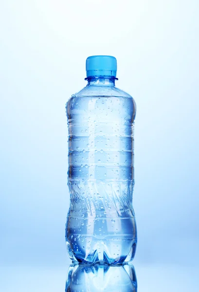 Plastikflasche mit Wasser auf blauem Hintergrund — Stockfoto
