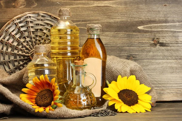 Olja i flaskor, solrosor och frön, på trä bakgrund — Stockfoto