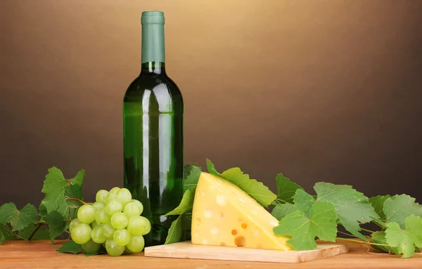 Botella de gran vino y queso sobre mesa de madera sobre fondo marrón — Foto de Stock